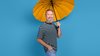 Lachender Mann mittleren Alters mit grauem Bart unter einem orangefarbenen Regenschirm