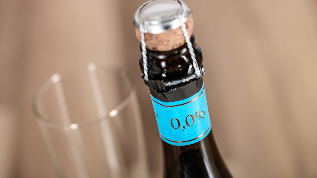 Ungeöffnete Sektflasche mit 0,00 Promille und Sektglas daneben