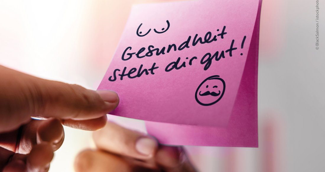 Finger halten pinkfarbenes Post-it mit Text "Gesundheit steht dir gut" am Spiegel