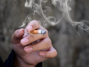 Frauenhand mit qualmender Zigarette in der Hand