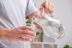 Wasserkaraffe aus der Wasser in ein Glas eingeschenkt wird
